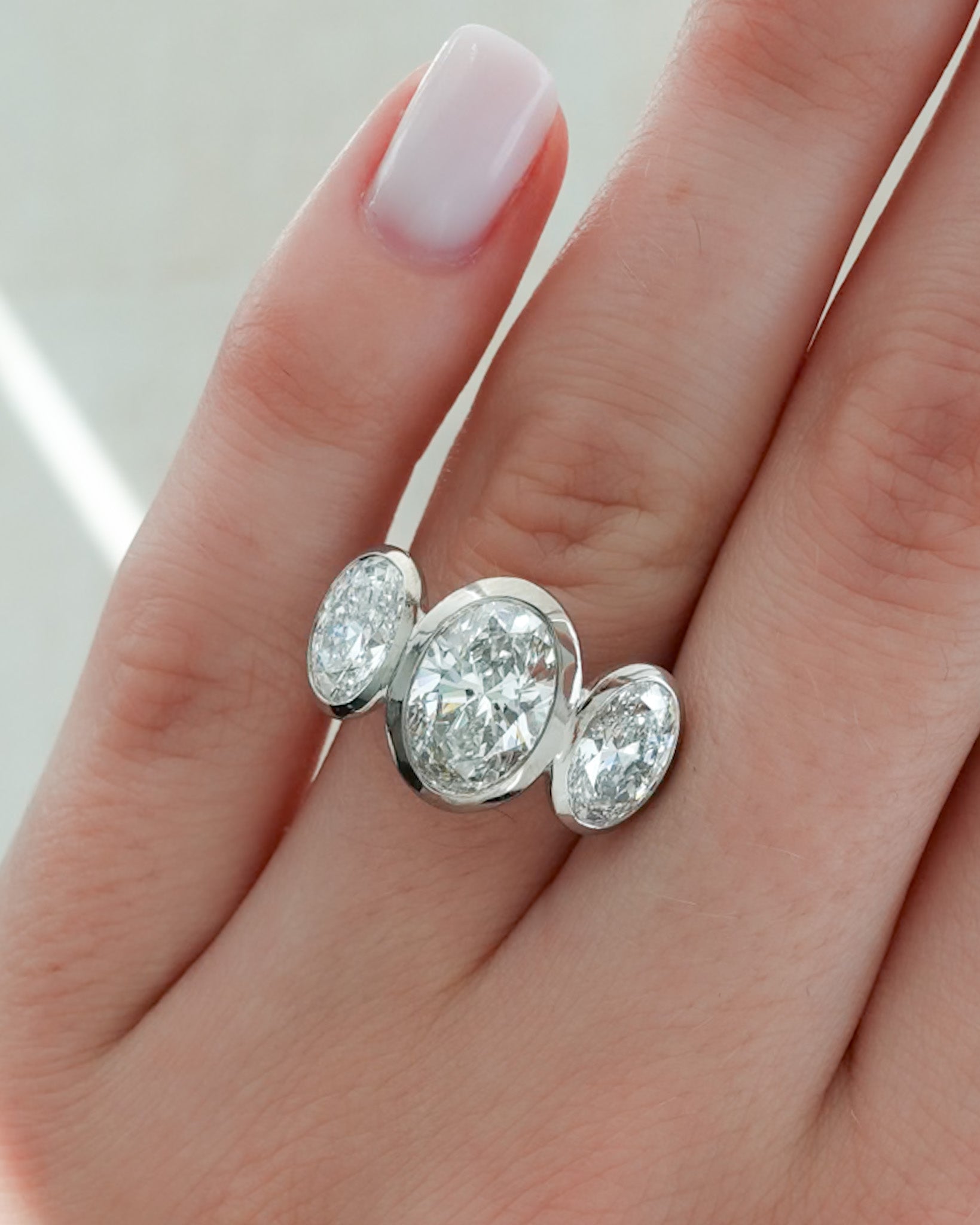 Penumbra Bezel Triad Engagement Ring With Oval Cut Diamonds